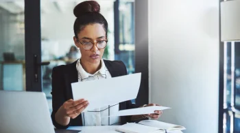 Woman in glasses reviewing documents in an office