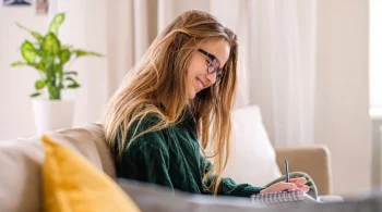 Woman in green sweater writing in a notebook