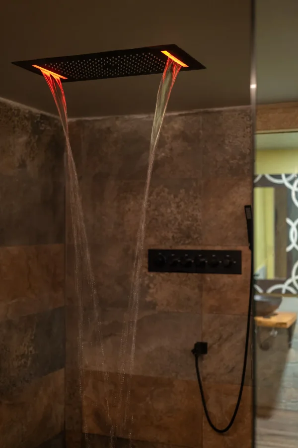 Water cascading under warm amber LED light in the Stimulos sensory shower room