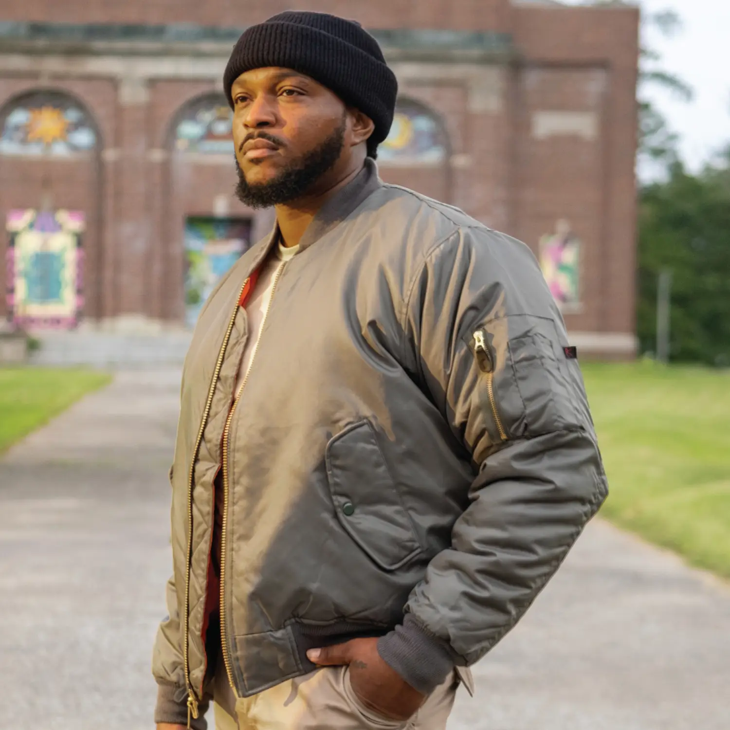 Man Wearing Bomber Jacket with Batches by Building