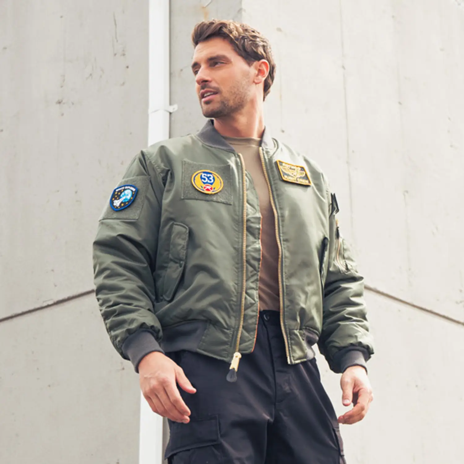 Man Wearing Bomber Jacket with Batches by Building