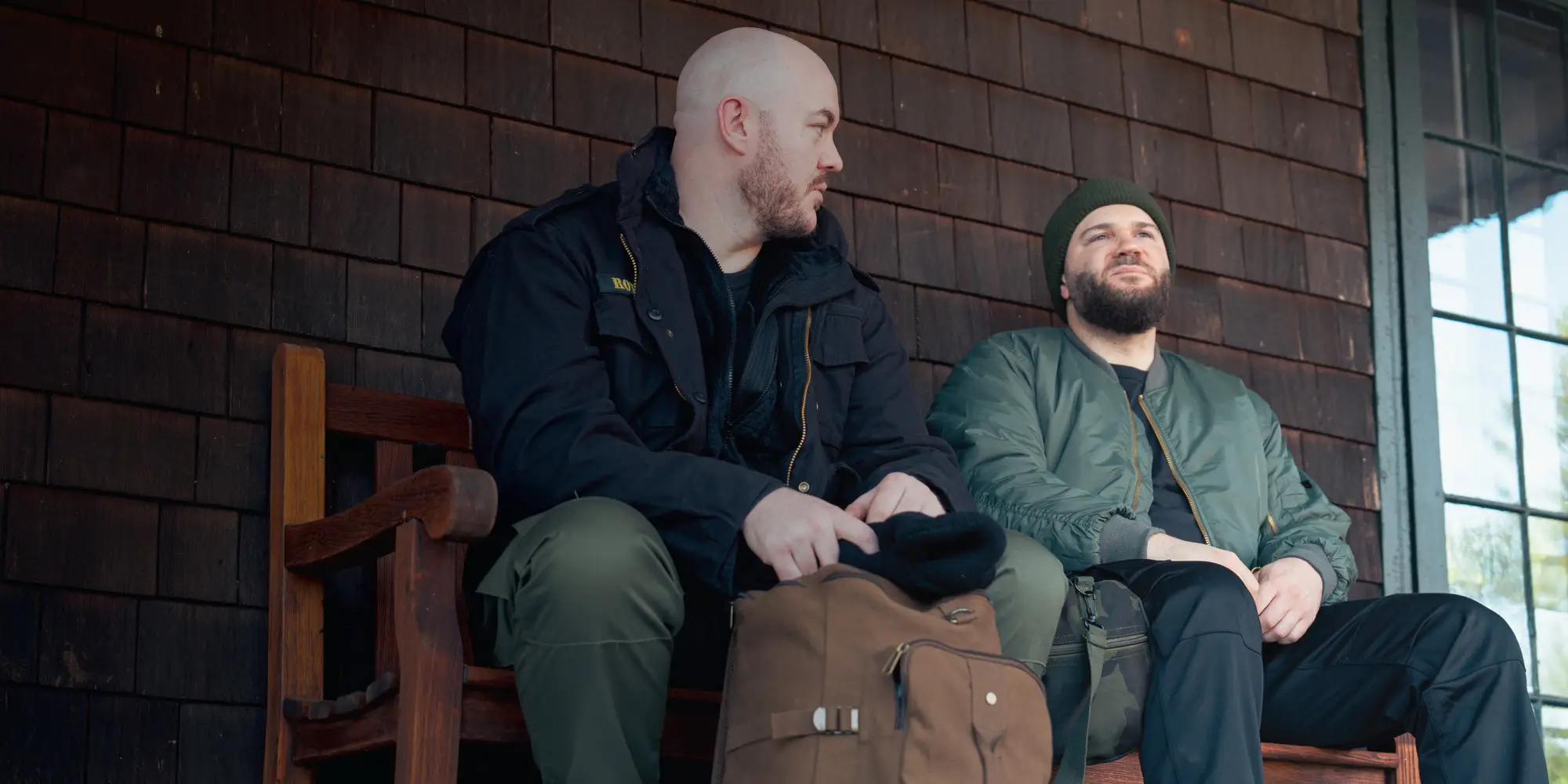 Two Men Wearing Casual Travel Jackets Sitting On Bench