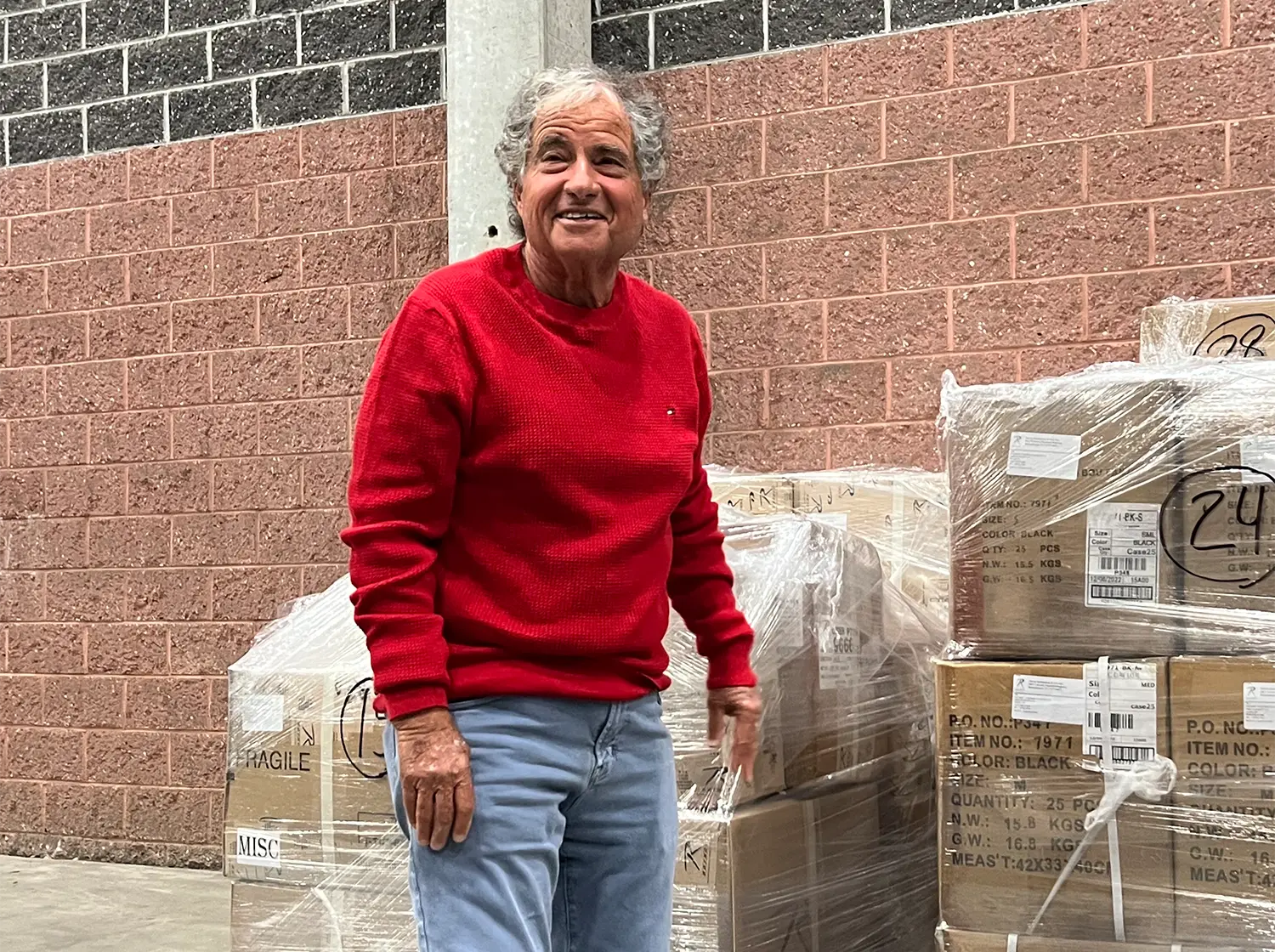 Howard Somberg Next to Wrapped Pallet of Items
