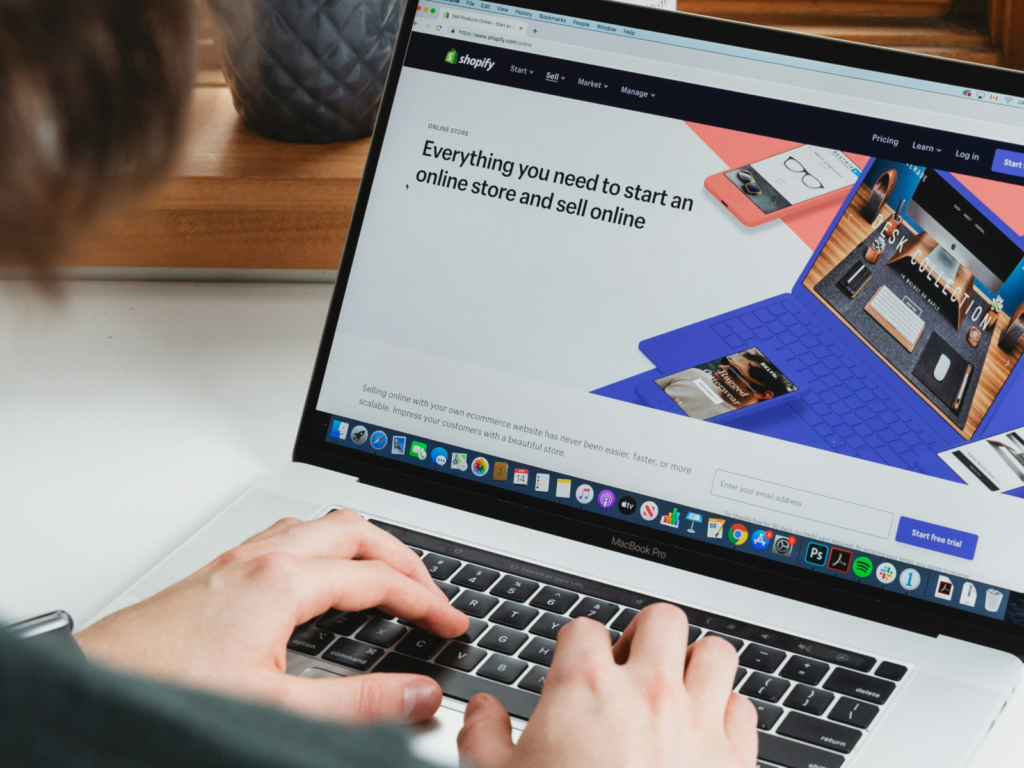 A man using a laptop and browsing through Shopify’s homepage.