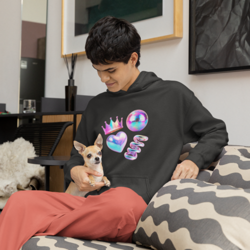A man in a black hoodie with abstract prints, sitting on a couch with a dog on his lap.