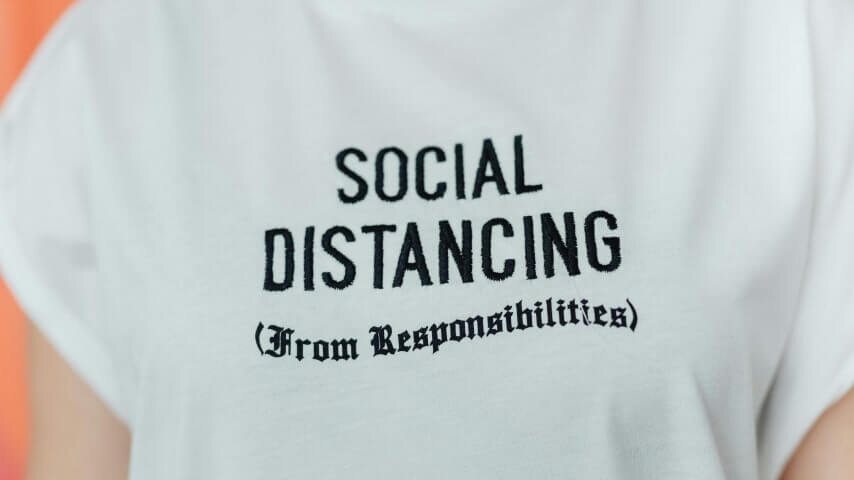 A custom white t-shirt with “Social distancing (from responsibilities)” text embroidered in the middle.