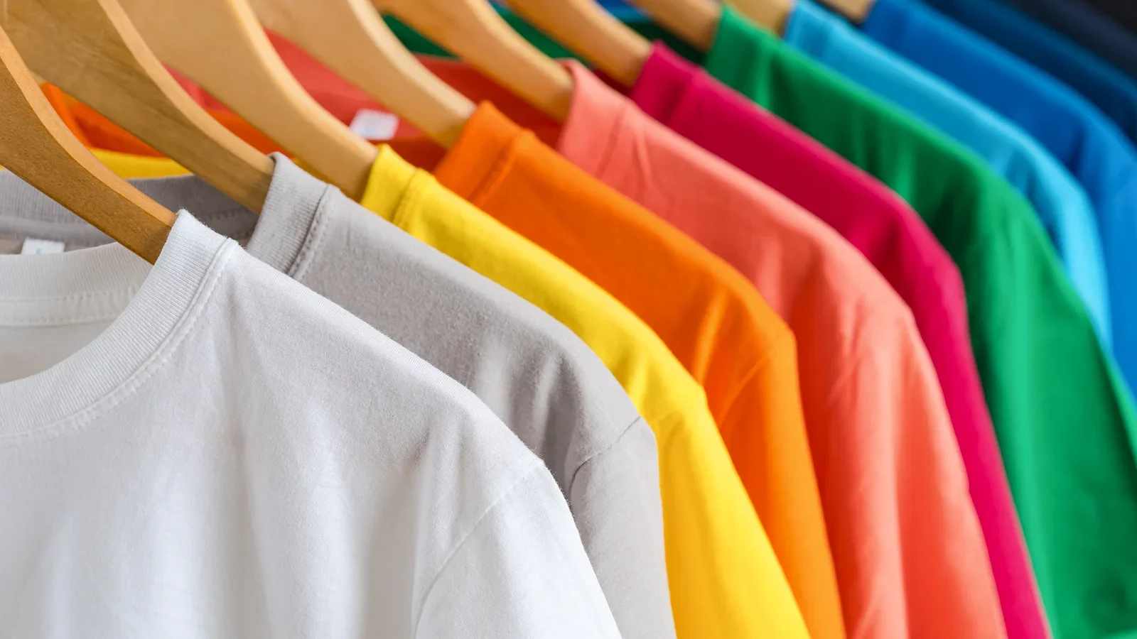 Different colored t-shirts on hangers.
