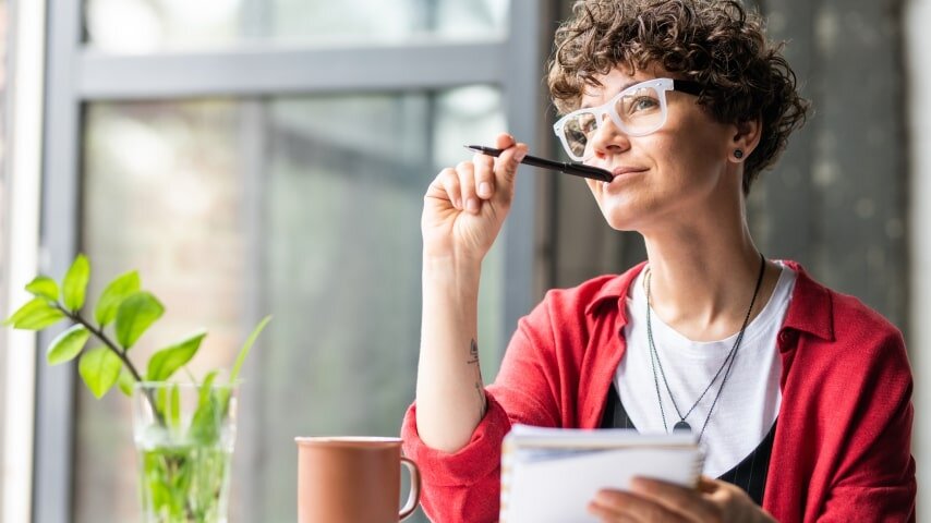 A woman taking notes with a thoughtful expression.