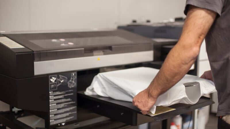 A man setting up a t-shirt printing press.