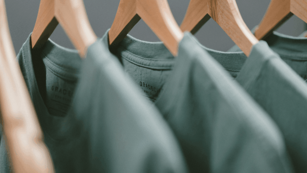 Green t-shirts displayed on hangers in a retail store, showcasing various styles and sizes.