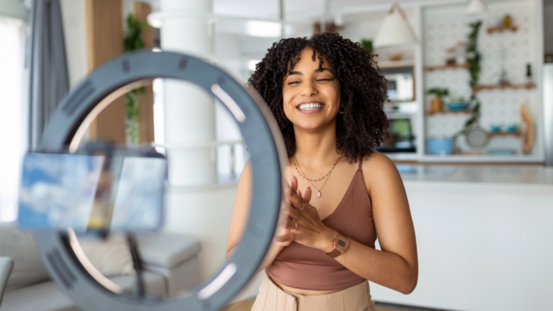 A smiling woman looks at a camera, capturing a moment with joy and enthusiasm.