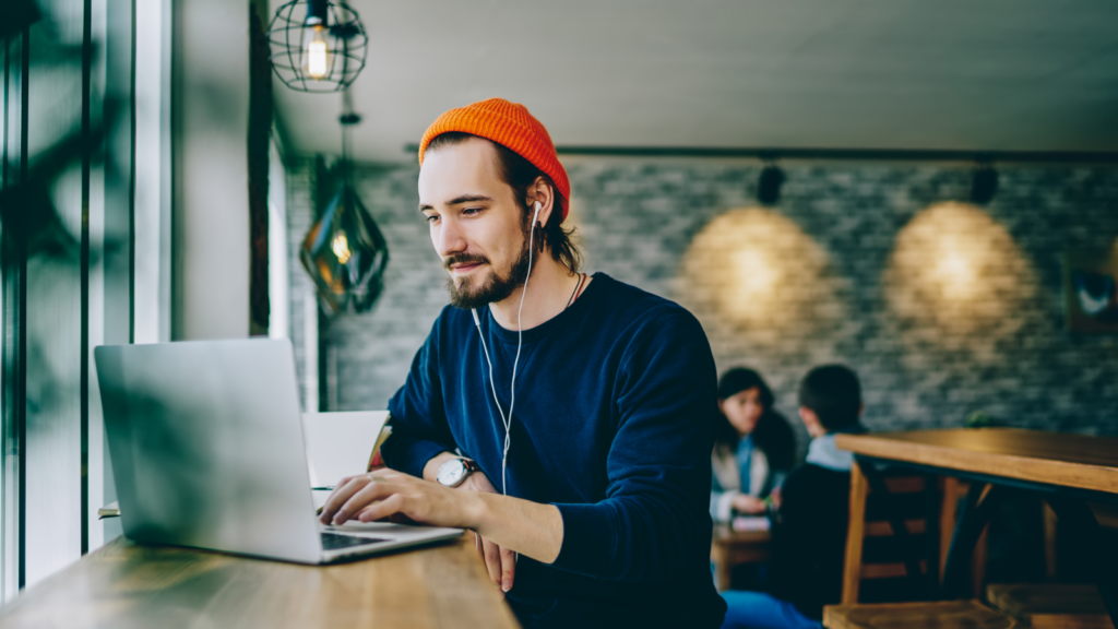 A man sitting in a cafe with his laptop on.