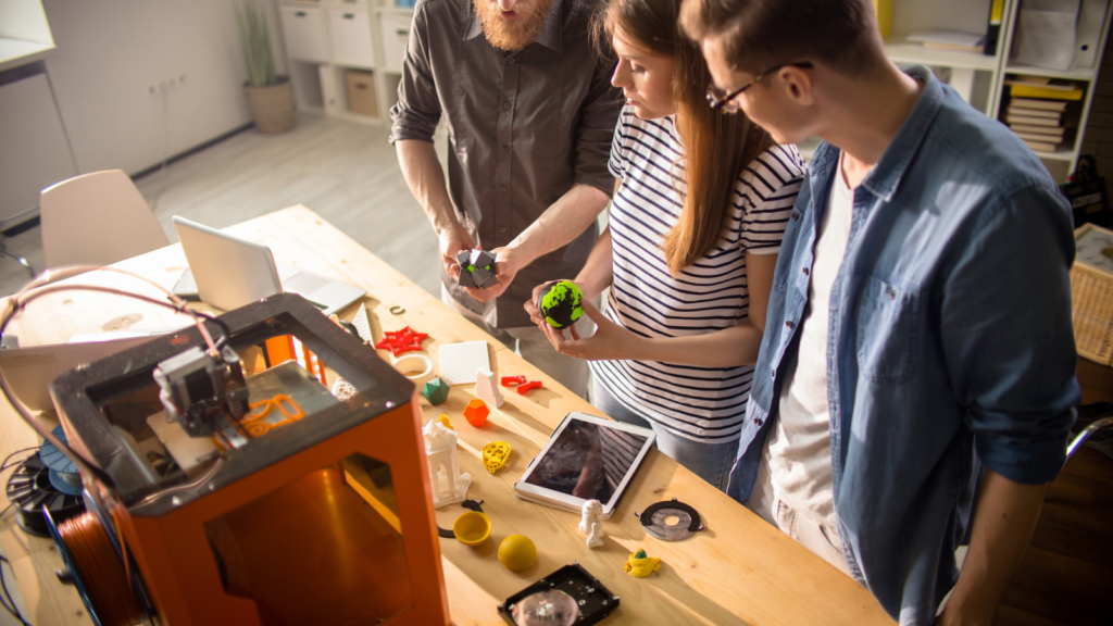 Three individuals collaborating on a 3D printer, focused on the printing process and adjusting settings.