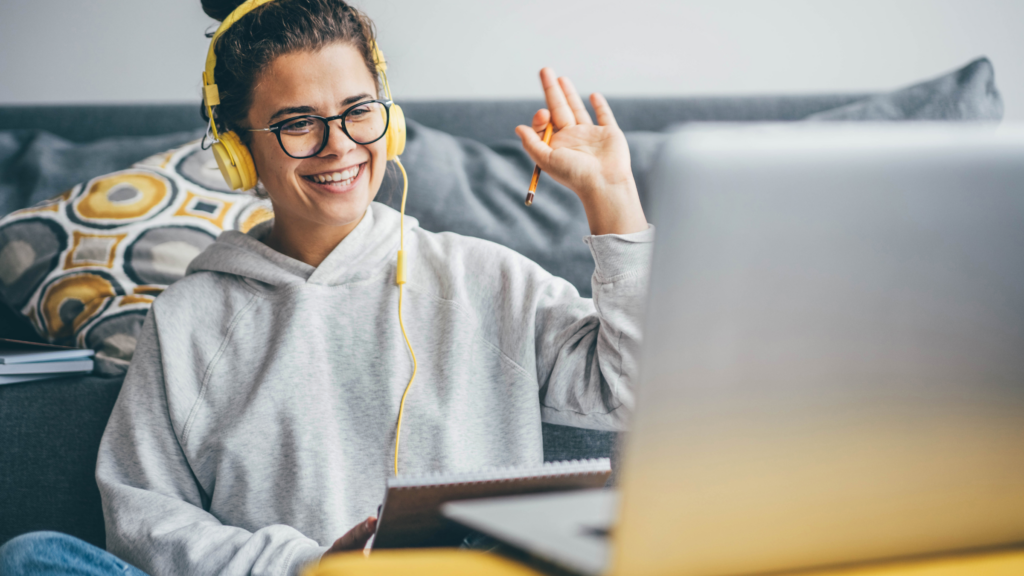 A woman wearing headphones is focused on her laptop and doing a video call.
