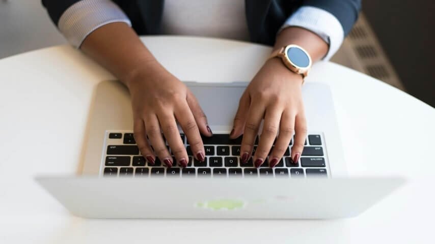 A woman typing on a laptop searching for suppliers.