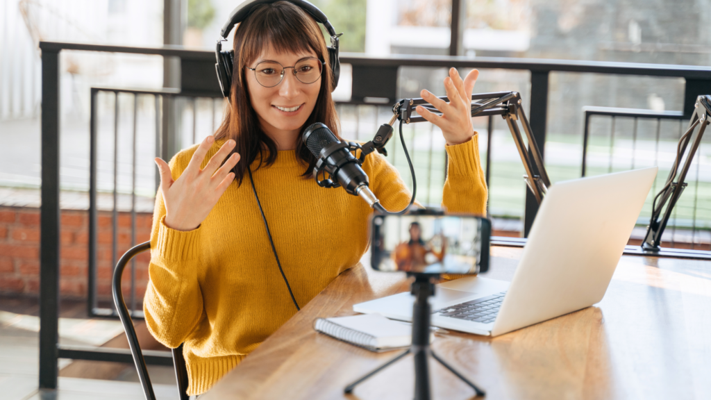 A woman in a yellow sweater sits at a table, doing online tutoring as a side hustle.