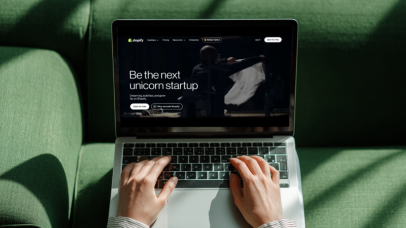 A person using a laptop with Shopify’s homepage on the screen.