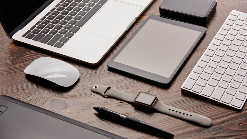 A laptop on a table surrounded by various tech accessories.