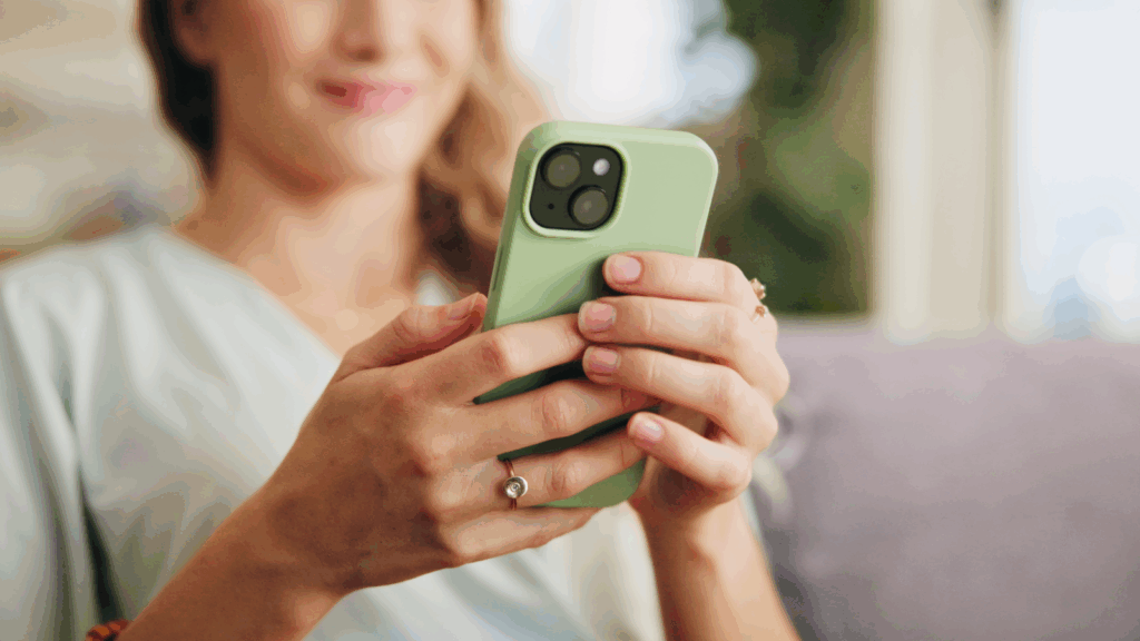 A woman holding a mobile phone in a green phone case in her hands.