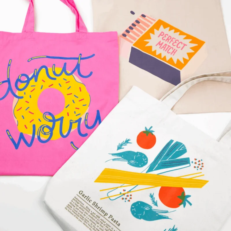 A pink bag with a donut graphic, a beige bag with "Perfect Match", and a white bag with kitchen ingredients and recipe text.