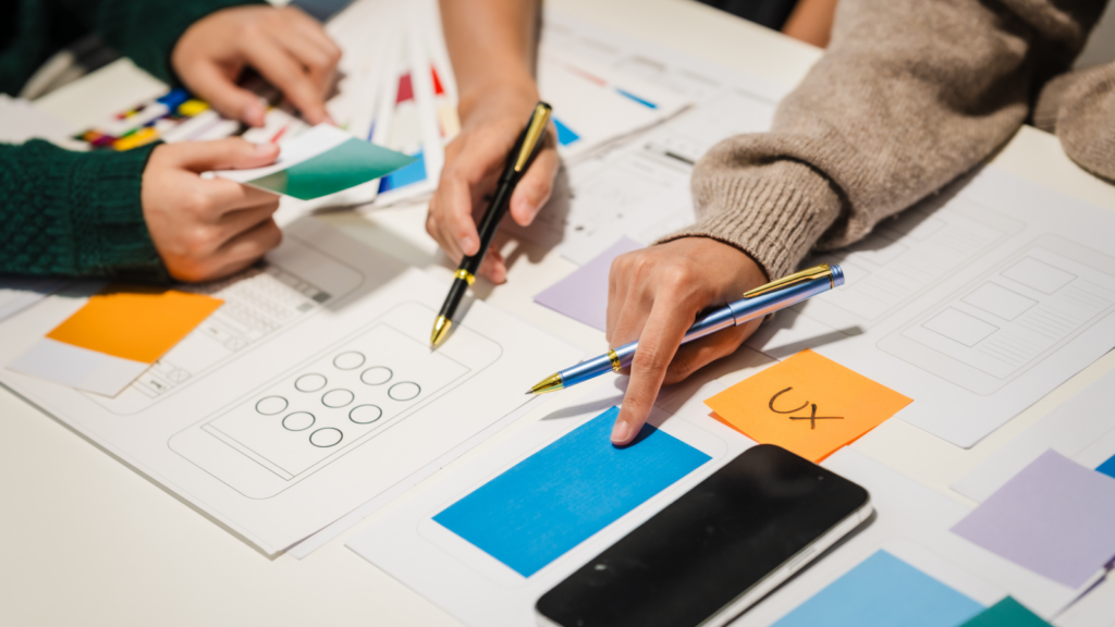 Two people planning a website structure using printed forms and sticky notes.