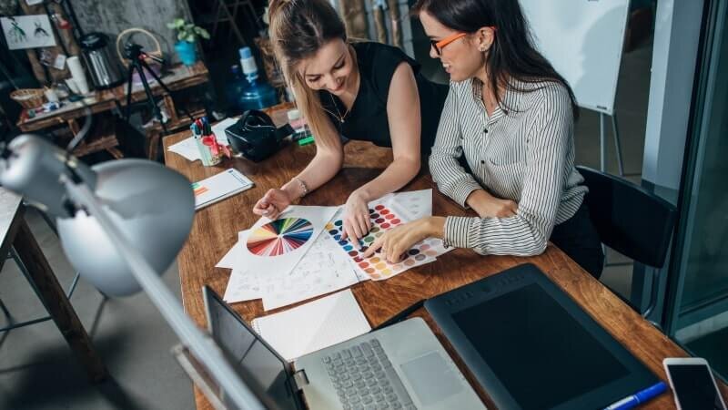 A woman showing a graphic designer her hoodie design ideas.