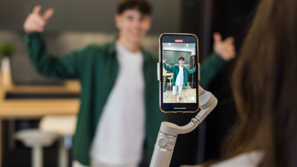 A mobile phone on a stabilizer recording a young man.