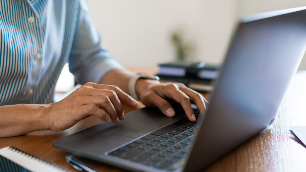Hands of a person above a laptop keyboard.