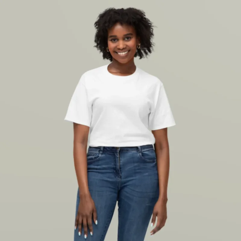 Smiling person with curly hair wearing a white T-shirt and blue jeans, standing against a plain gray background, exuding confidence and warmth.
