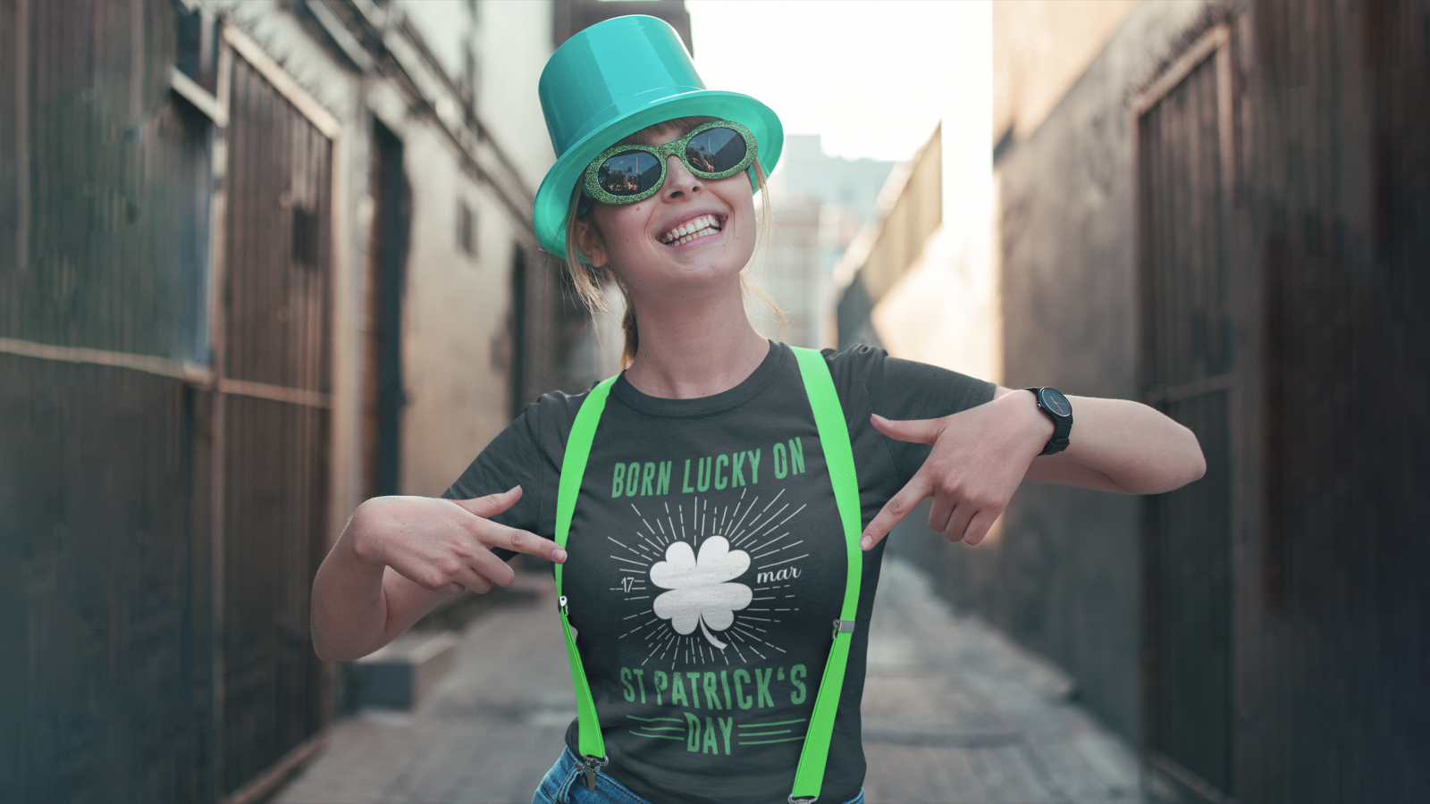 A woman in a festive St. Patrick's Day shirt and hat, smiling and celebrating the holiday.