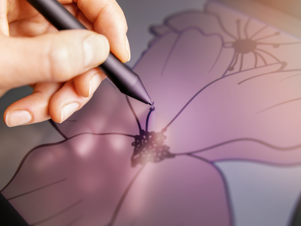 Close-up of a hand drawing a flower with a stylus on a digital tablet.