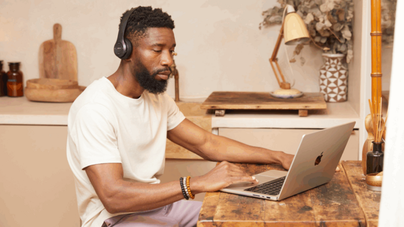 A man is sitting at a kitchen table and using a laptop to find information on product customization.