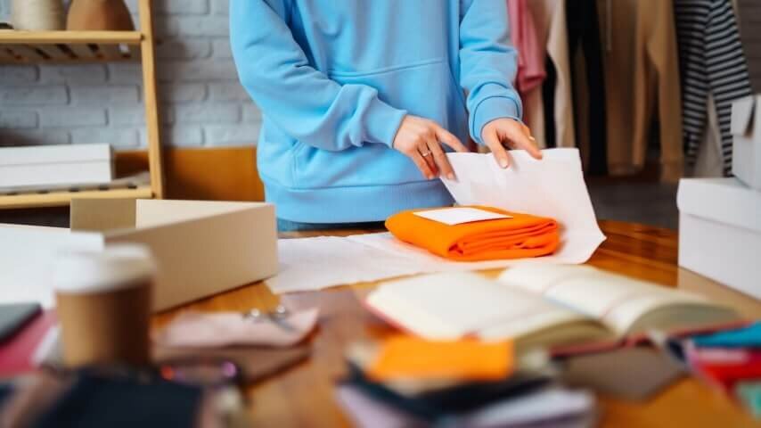 A person packaging clothing items with customized inserts.