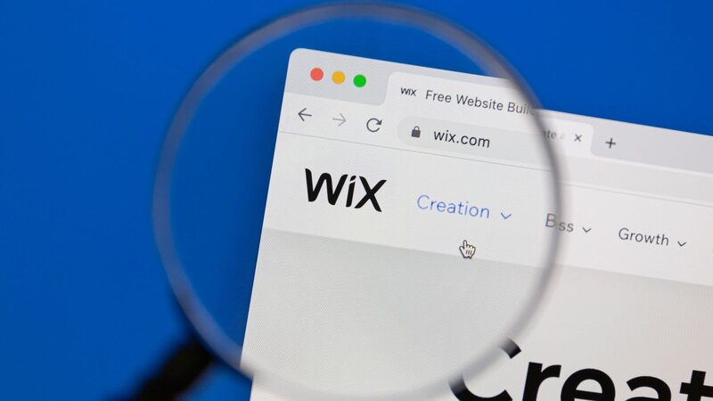 A close-up view of the Wix website on a computer screen, featuring the Wix logo highlighted, with a magnifying glass effect.