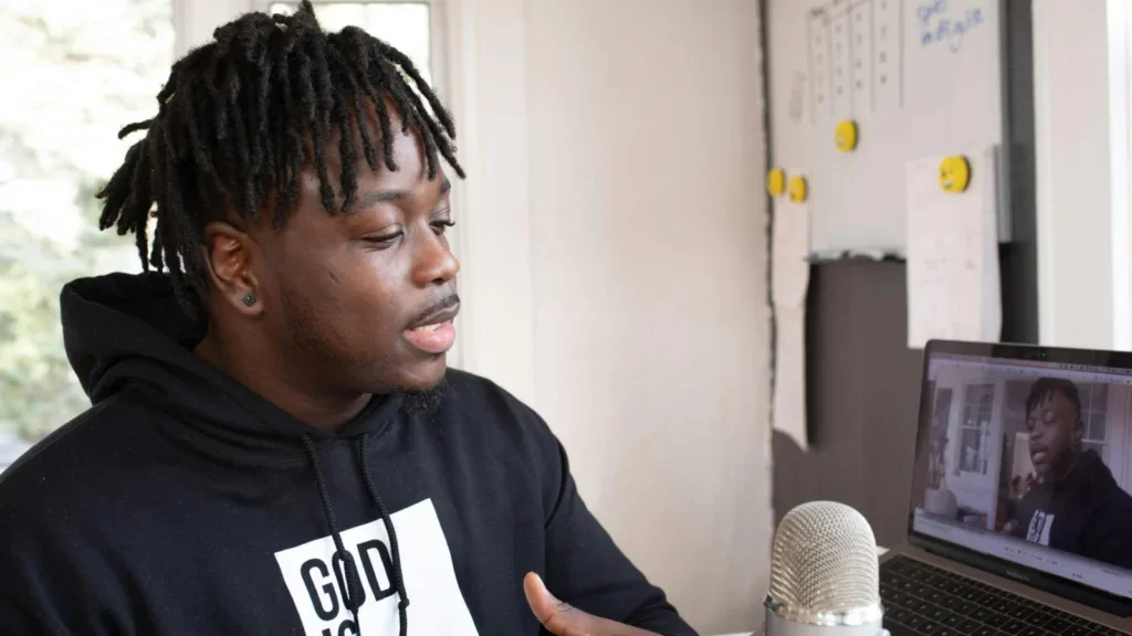 A man in a black hoodie recording a podcast.
