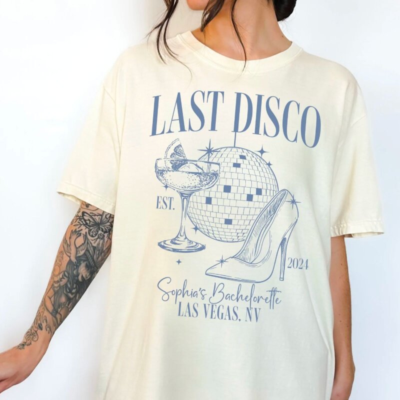 A black t-shirt featuring a colorful graphic of a disco ball and the text "Last Disco" in retro font.