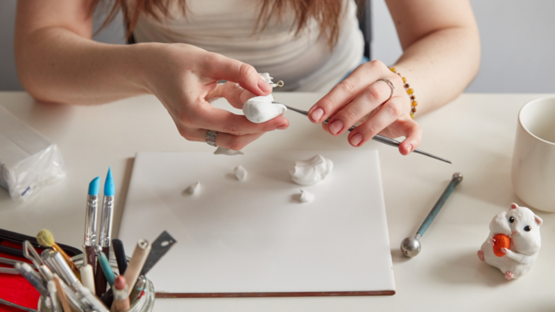 A woman making hamster figures from white clay.