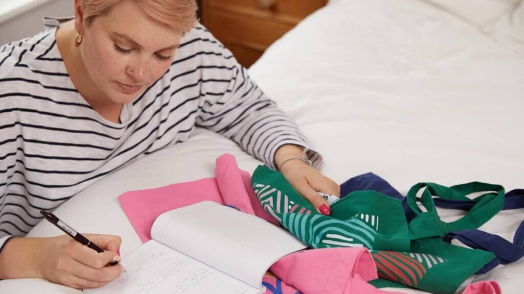 A woman checking product quality and noting things down in a notebook.