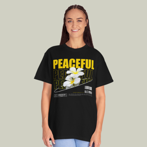 A woman wearing a black “Peaceful” t-shirt on a light olive green background.