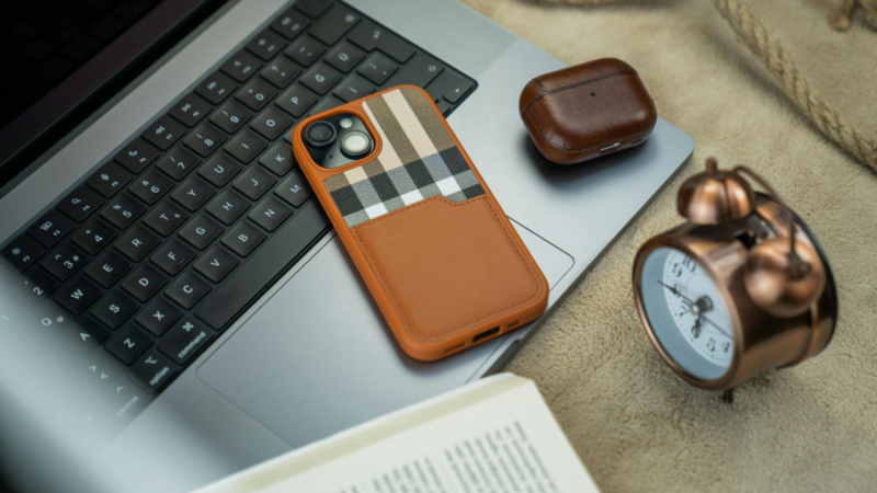 A smartphone in a custom leather phone case lying on top of a laptop keyboard.