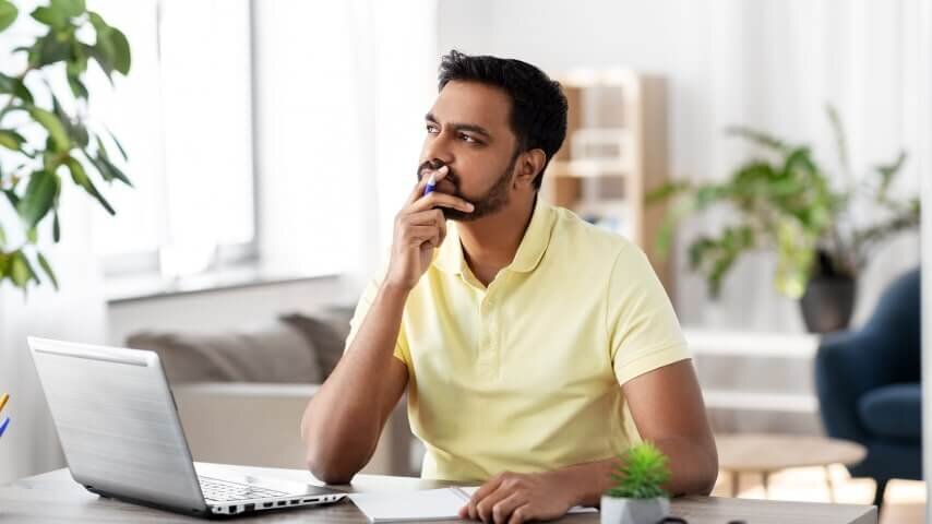A thoughtful man sitting at his desk and looking into the distance.