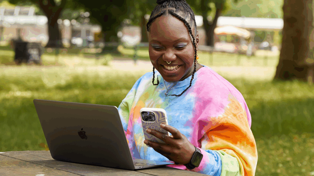 A woman smiles while working on her laptop.