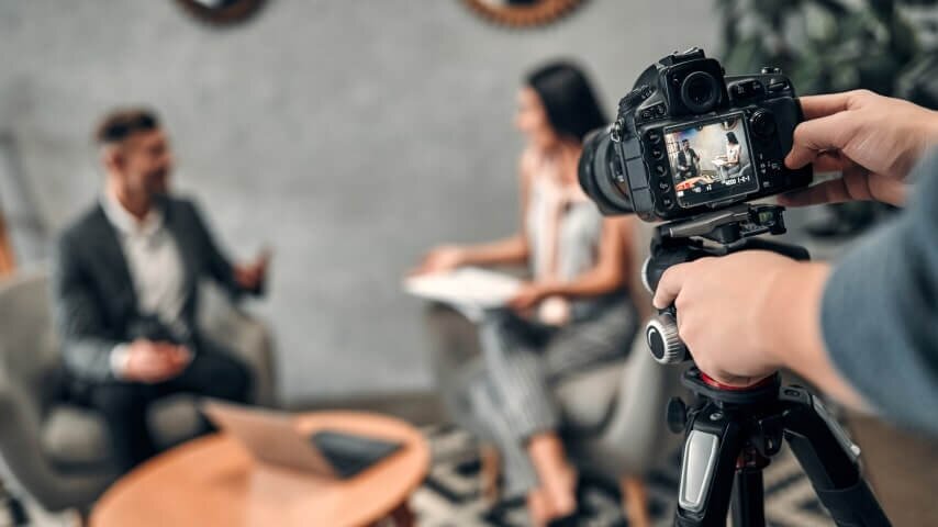 A person filming two individuals engaged in an interview.