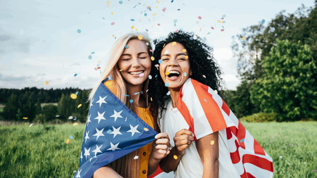 Two smiling women holding an American flag, celebrating the 4th of July.