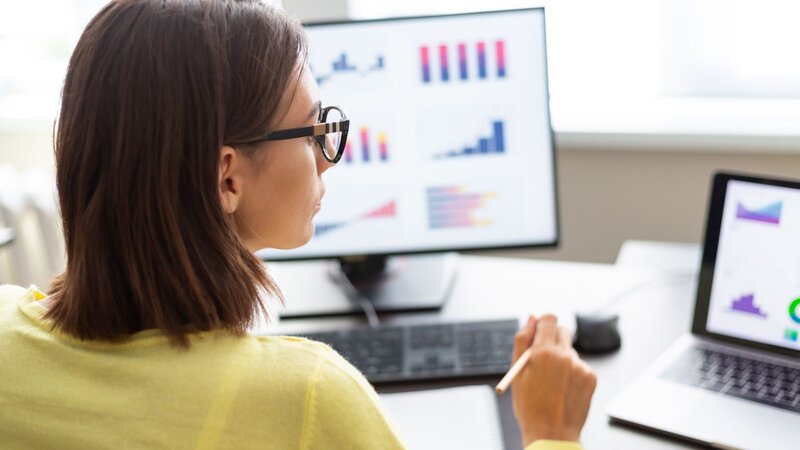 A woman analyzes graphs displayed on a computer screen, focusing intently on the data presented.