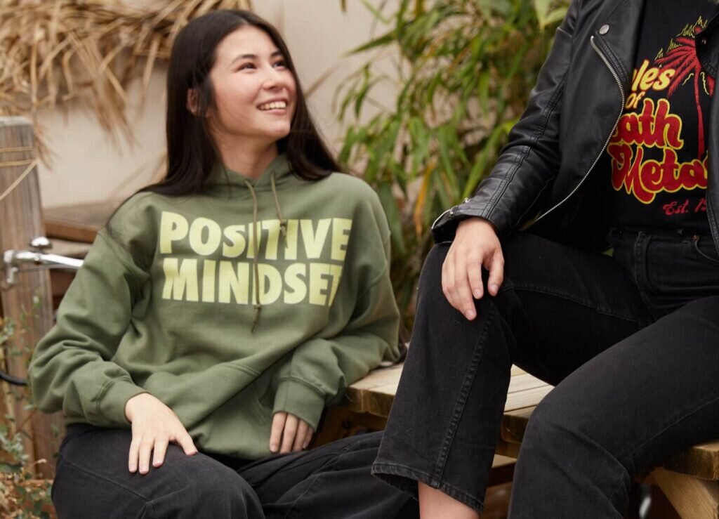 Two women talking while wearing custom hoodies with text and illustration prints.