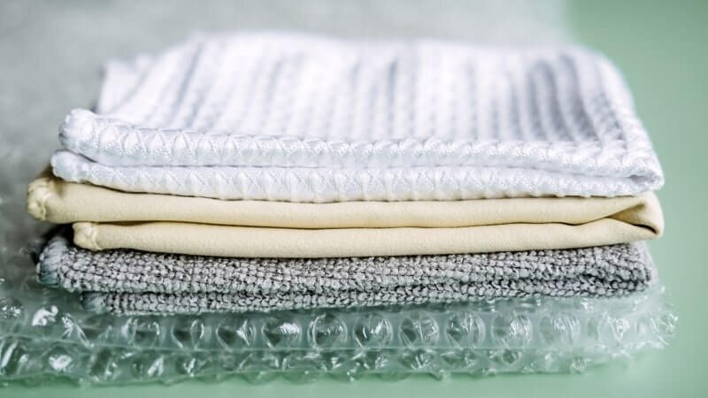 A stack of garments made from different types of polyester blend fabrics.