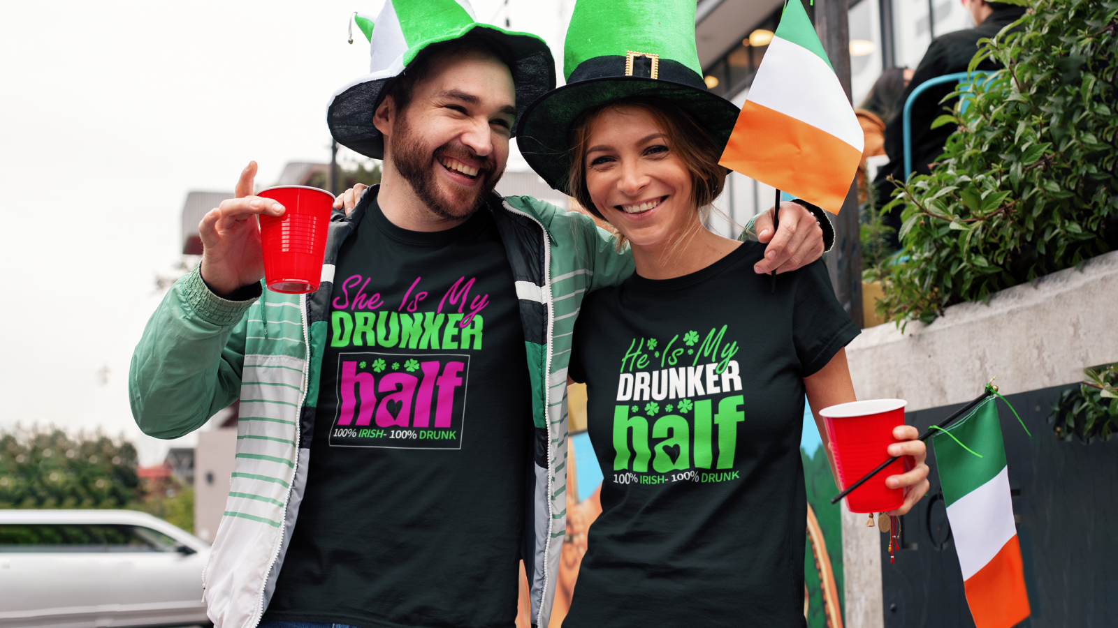 A cheerful couple in St. Patrick's Day hats, wearing “He’s/She’s My Drunker Half” t-shirts.