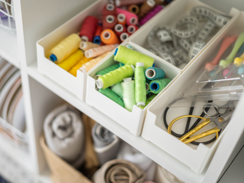 A neatly organized white cabinet displaying a range of sewing supplies.