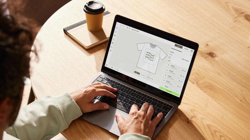 A person using a laptop to create a custom t-shirt with Printify’s Product Creator, accessing free print designs.